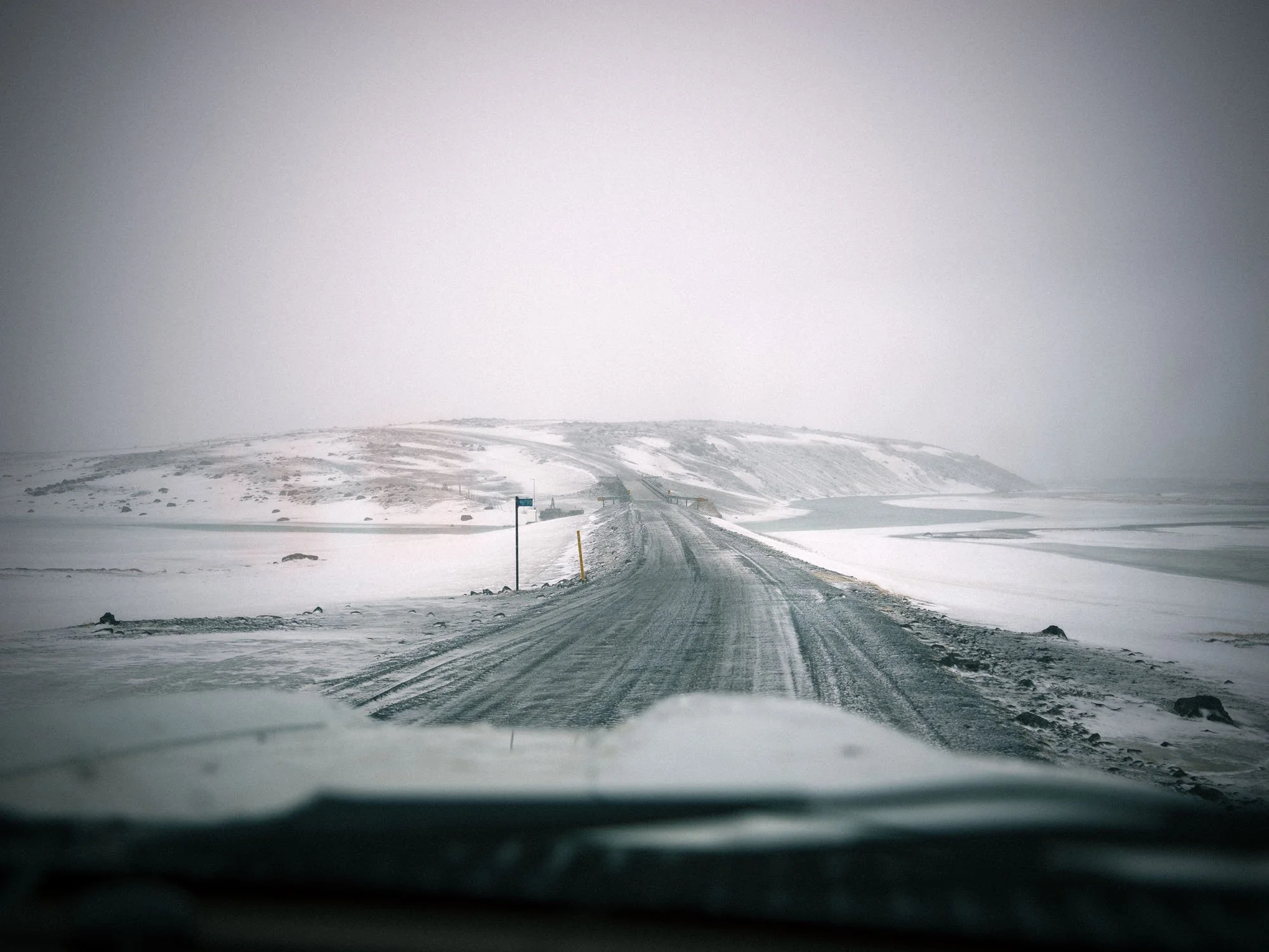 Snow-covered road viewed through a vehicle windscreen