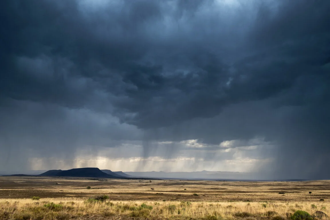 Colour photograph of a dramatic storm over the Karoo landscape, South Africa, with expansive skies and arid terrain, by Peter Delaney