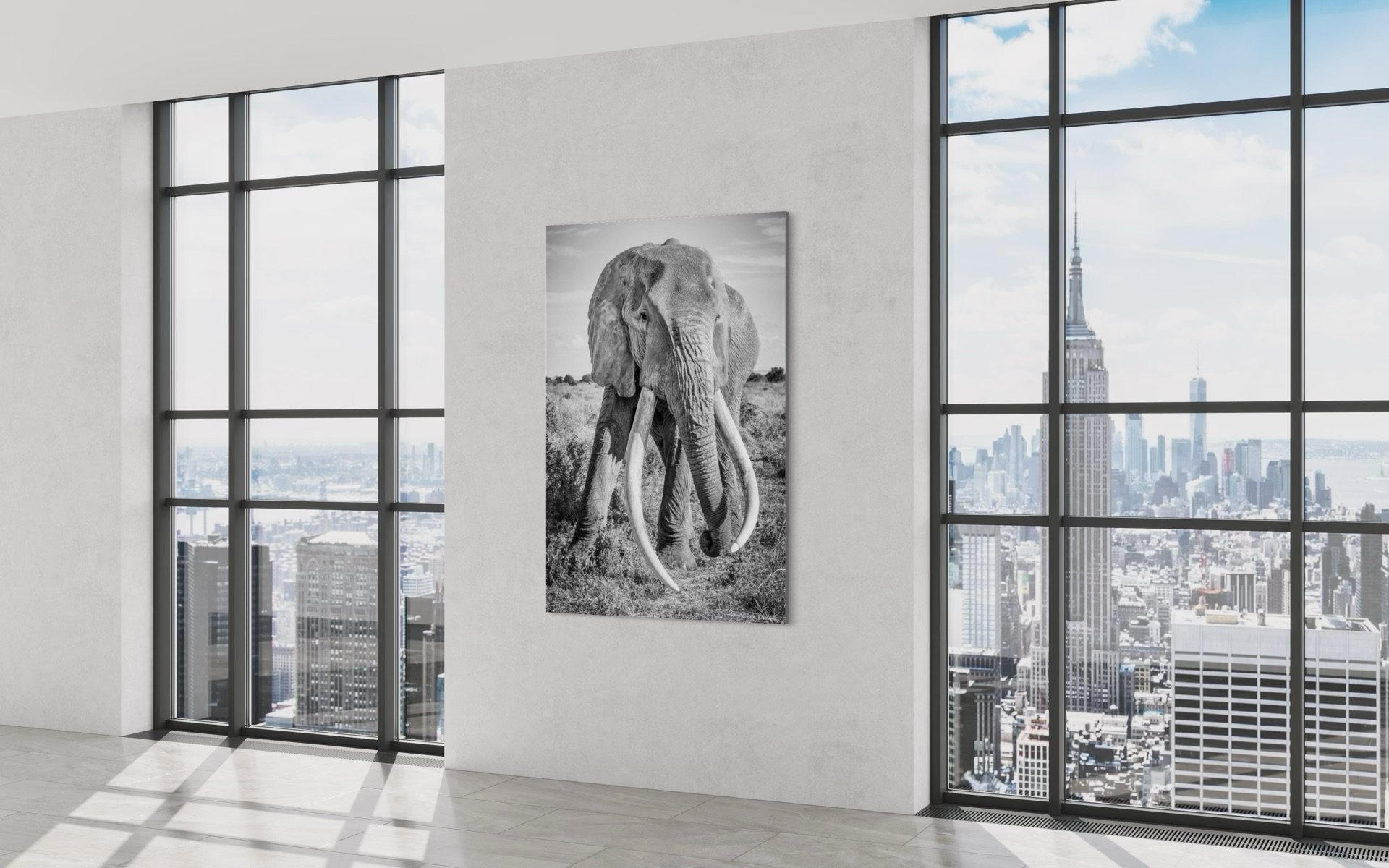 Interior of a high-rise apartment with large glass windows showing a city skyline, a black and white elephant photograph mounted on the wall, and sunlight casting shadows on the white tiled floor.