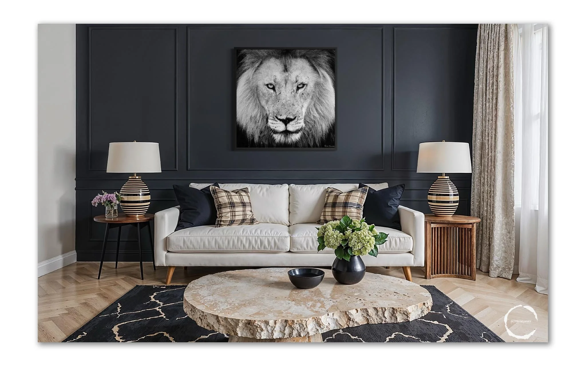Modern living room with a white sofa, black and plaid pillows, a large stone coffee table, black and white striped lamps on wooden side tables, and a black and white lion portrait on a dark navy wall.