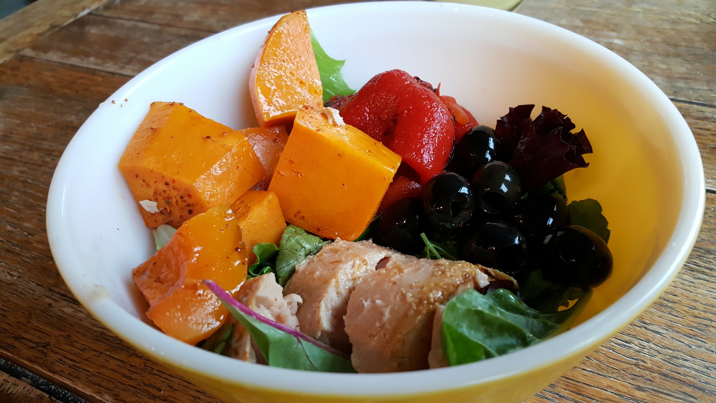Salad bowl of butternut squash, greens, roasted red peppers, tuna and olives