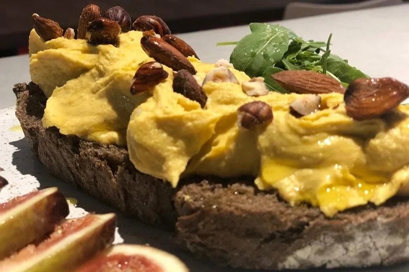 Toast Homus: Pão de campanha orgânico malte, homus de abóbora, mix de castanhas, figo, mel e rúcula.
