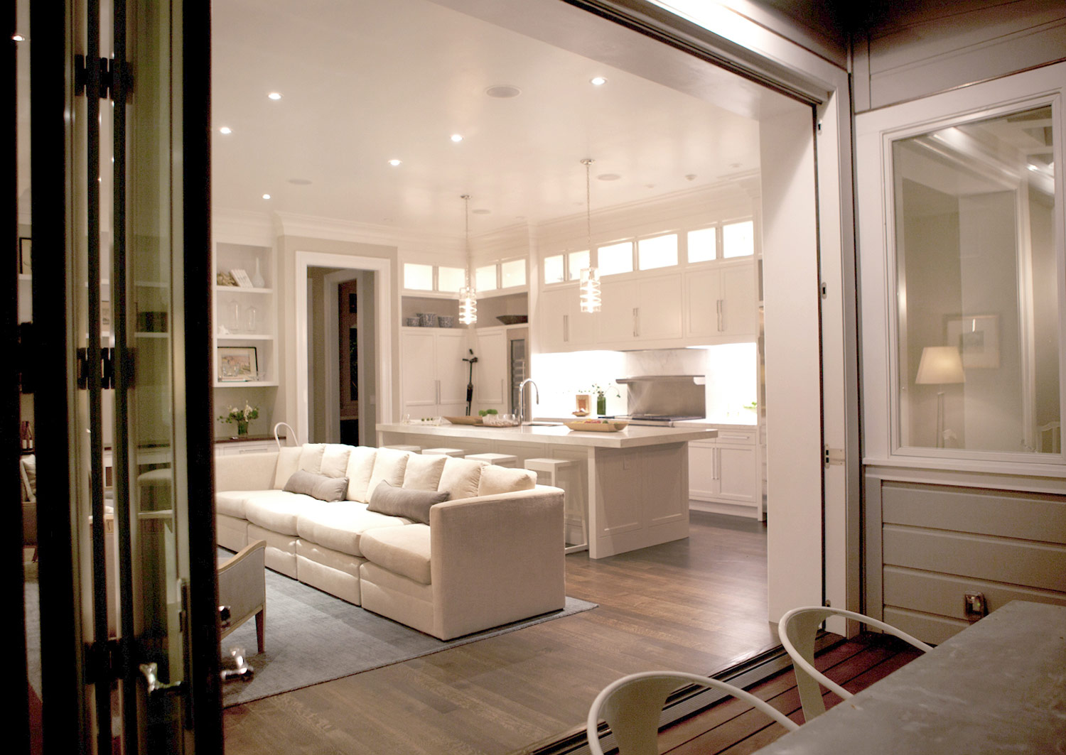 living room, kitchen, open floor plan, hardwood floors, white kitchen, pendants, marble counters, built in shelving, cabinetry