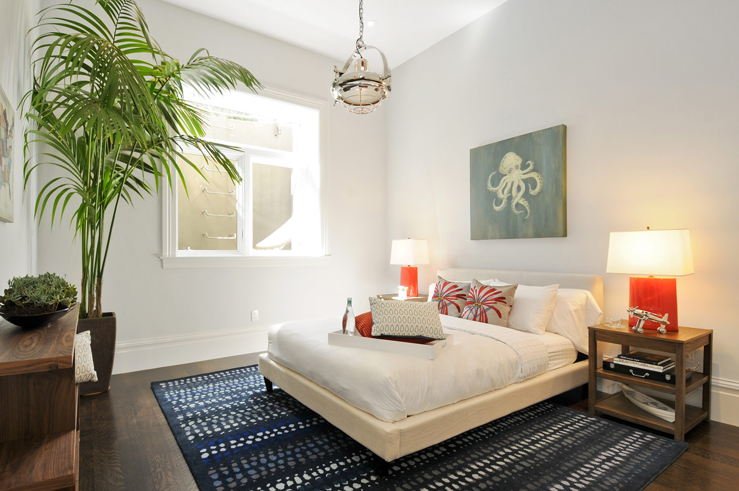 beachy bedroom, blue rug, fabric bedframe, bedside table lamps, indoor plants, artwork
