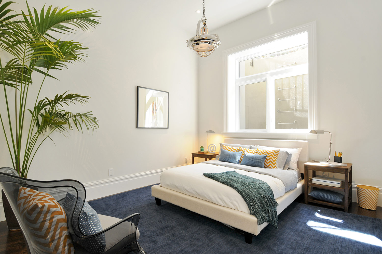 beachy bedroom, blue rug, fabric bedframe, bedside table lamps, indoor plants, artwork