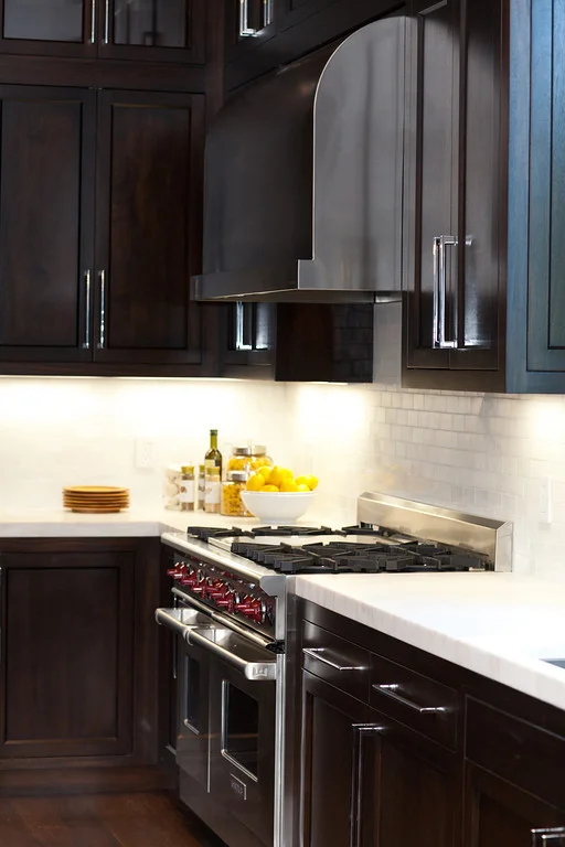 dark cabinetry, stainless steel, marble counters, barstools, kitchen pendants, prep sink, polished chrome faucet, wolf range