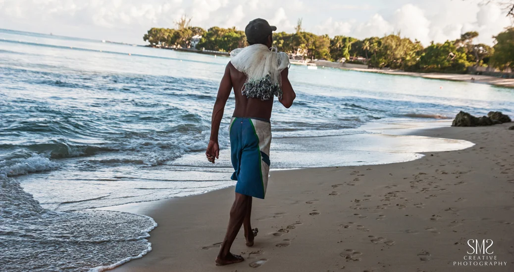Fisherman walking along Barbados beach1