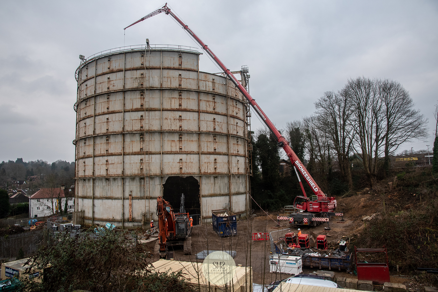 A piece from the side of the gas holder removed so the crane has access to the furthest part of the roof to complete the top removal