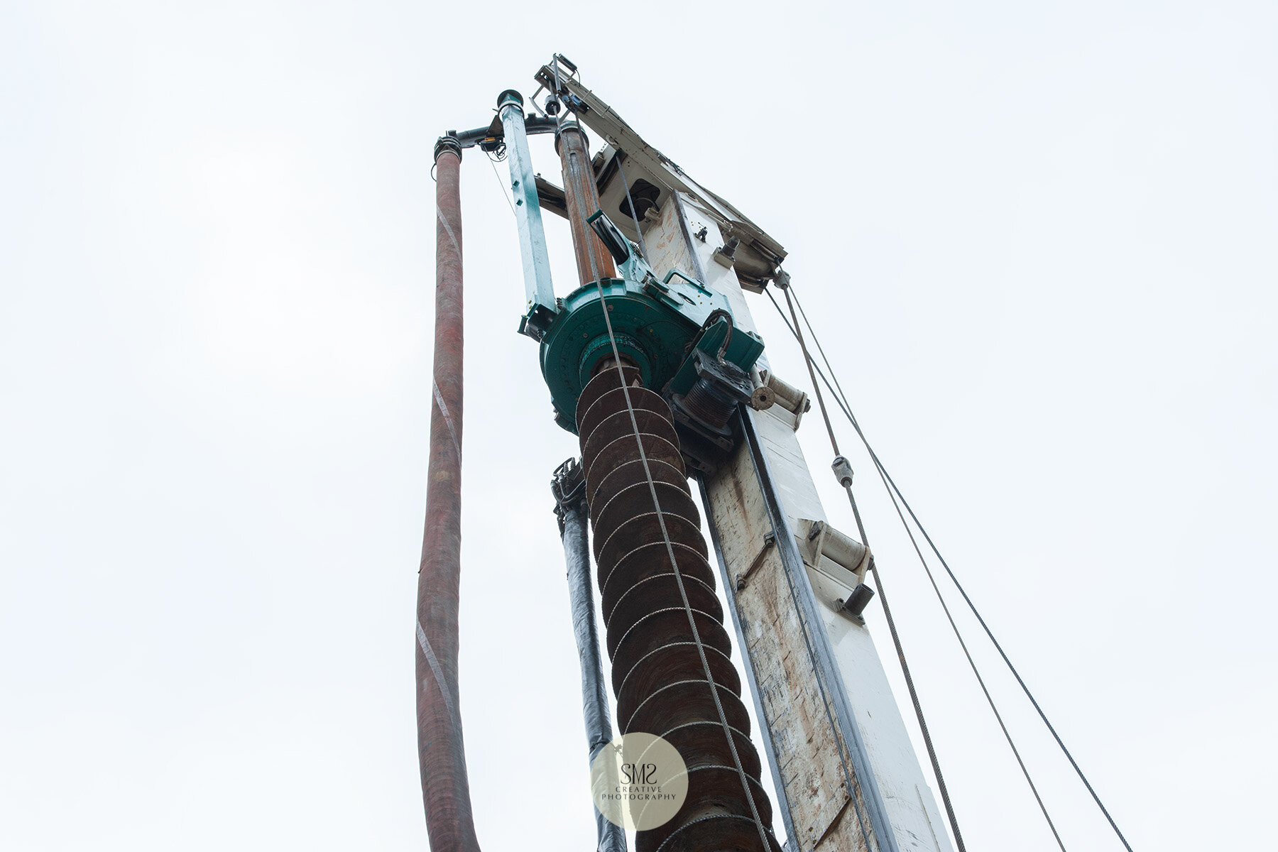  The hose at the top of the piling rig works in unison with the drill (the auger), a swift process in preparation for a metal ‘cage’ to be inserted in the hole. 