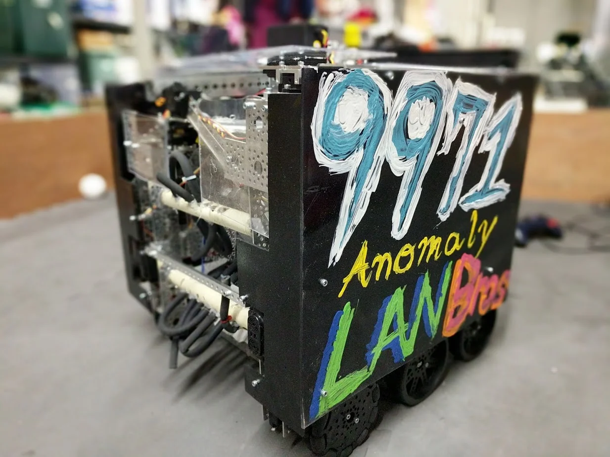 Anomaly was our 2nd robot created in the Velocity Vortex season. Throughout the lifespan of Morton, we were planning this robot as well. We begun to plan this robot in November after our PA Eastern Qualifier. After our last New Jersey meet of the season, we had a 1 month break until our next tournament. In that month we worked tirelessly to create Anomaly. Anomaly featured the same 6 wheel drive as Morton, but with a few changes. The first thing we changed was adding doubled up omni-wheels in the front of the robot to allow for better turning. We also increased the gear ratio from 1.5:1 to 2:1 so we would be even faster on the field. For our particle shooting, we switched from a dual flywheel shooter to just one flywheel. We switched to one flywheel because of the backspin created on the particles after they were launched. This allowed the particles to come back to the general area of our robot once they landed and it improved our cycle times even further. Along with the new shooter and updated drivetrain, we also added a linear slide system to cap the ball on the center vortex. We used a mix of Rev 15mm extrusion, drawer slides and Actobotics parts to create our lift. With our lift we were able to average a capping time of 12 seconds. We also had improved autonomous programs that continued to score all autonomous objectives but in a faster and more efficient way. By the World Championships in St. Louis, we were averaging 14-16 particles in each match. We consistently hit the 200+ point range with our highest scoring match being a 275 pt. match scored at a New Jersey scrimmage right before worlds. It took a lot of hard work and planning to create this robot, but in the end it was worth it and we are immensely proud of what we learned and created during Velocity Vortex.