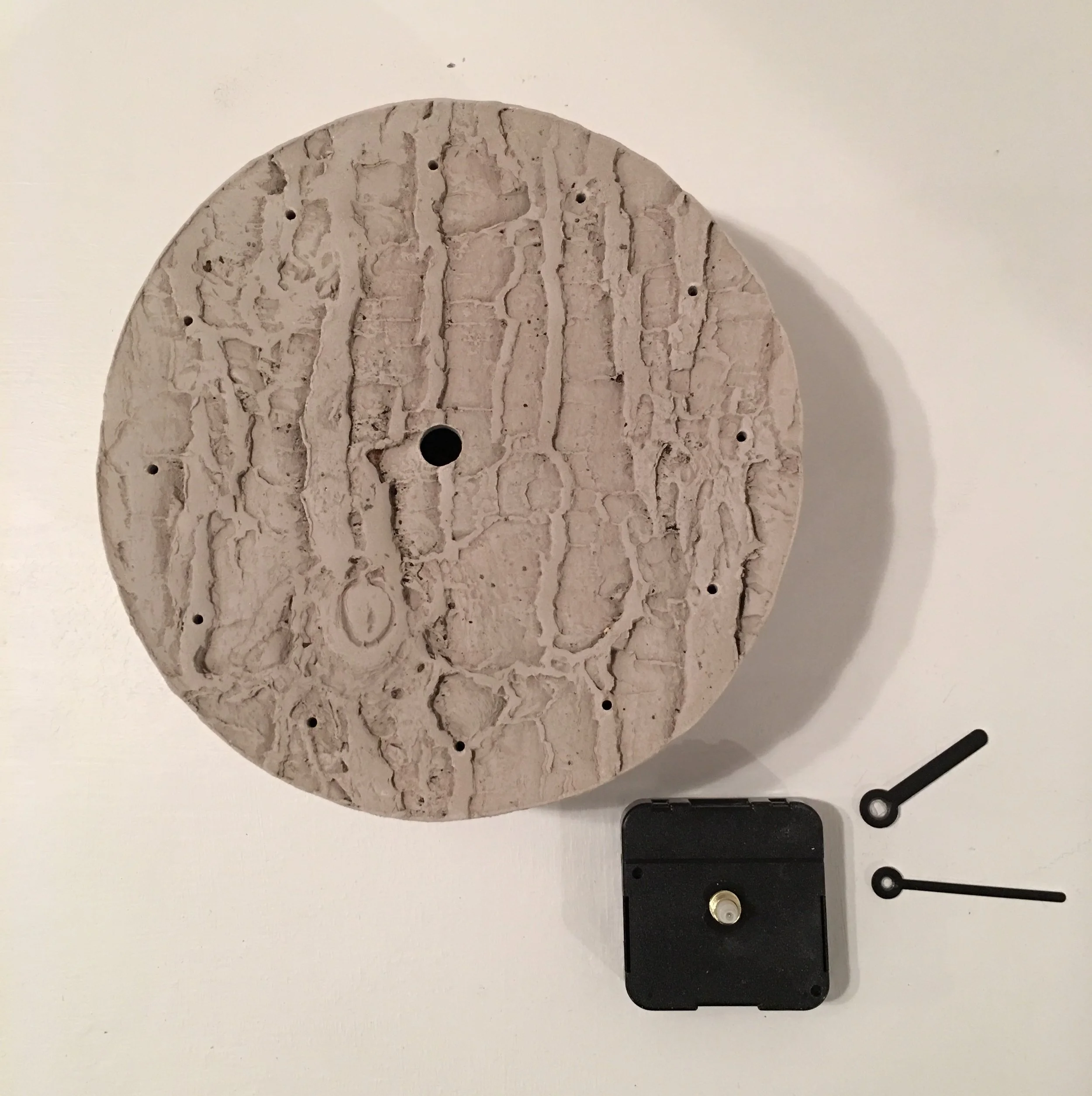 Wall hanging clock with impressed tree bark motif.