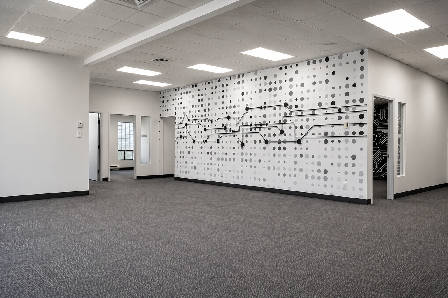 Empty office space with white walls, gray carpet, and a decorative wall featuring a circuit board pattern and black dots.
