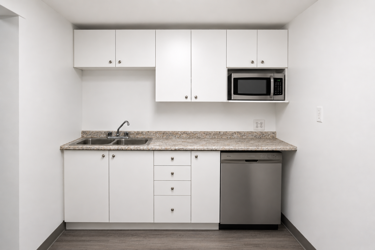 Minimalist kitchen with white cabinets, a marble-like countertop, a stainless steel sink, microwave, and dishwasher.