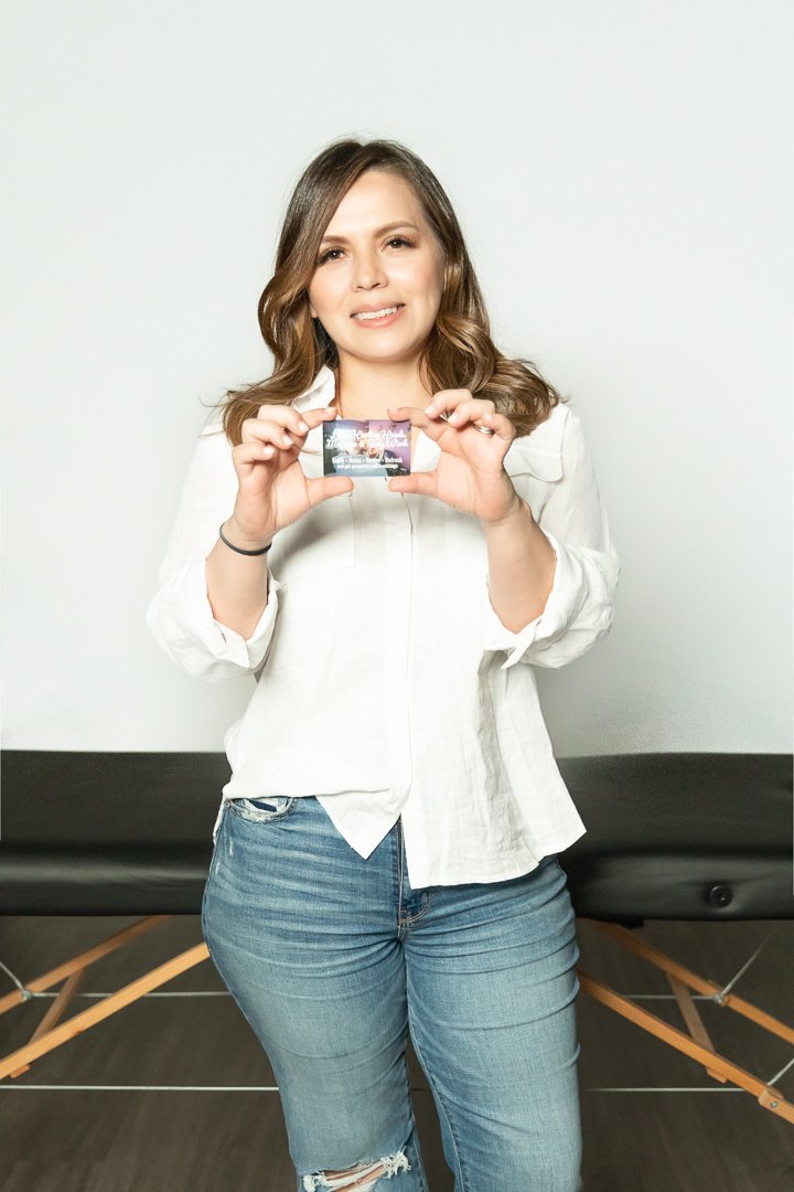 A woman holding a gift card from lilies healing hands massage & body work and smiling