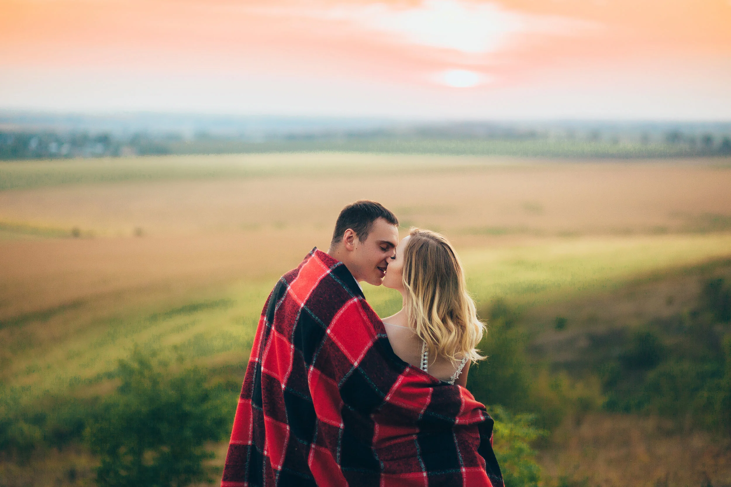 Beautiful bride and groom embracing each other in the mountains. Very beautiful white wedding dress designer. Beautiful couple in love on the rocks. Sunset