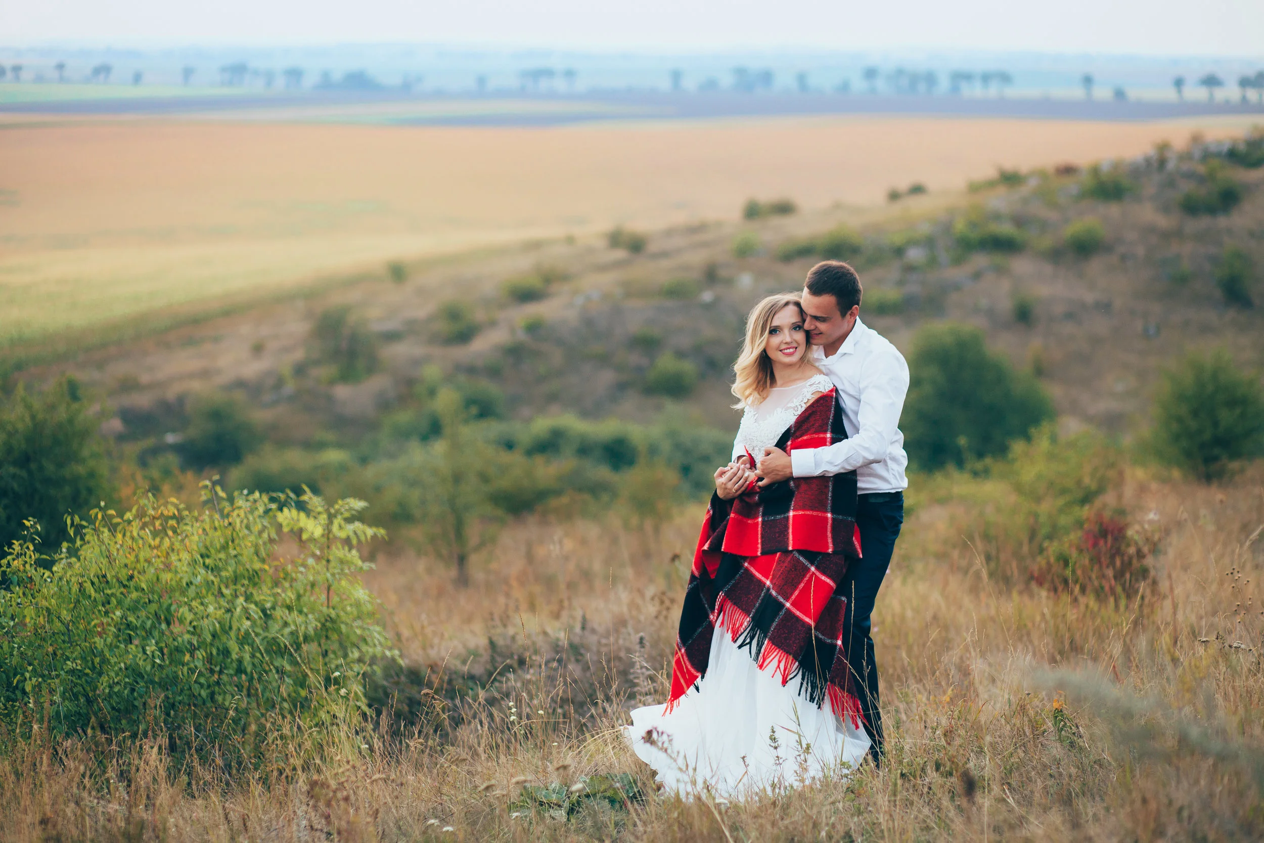 Beautiful bride and groom embracing each other in the mountains. Very beautiful white wedding dress designer. Beautiful couple in love on the rocks. Sunset