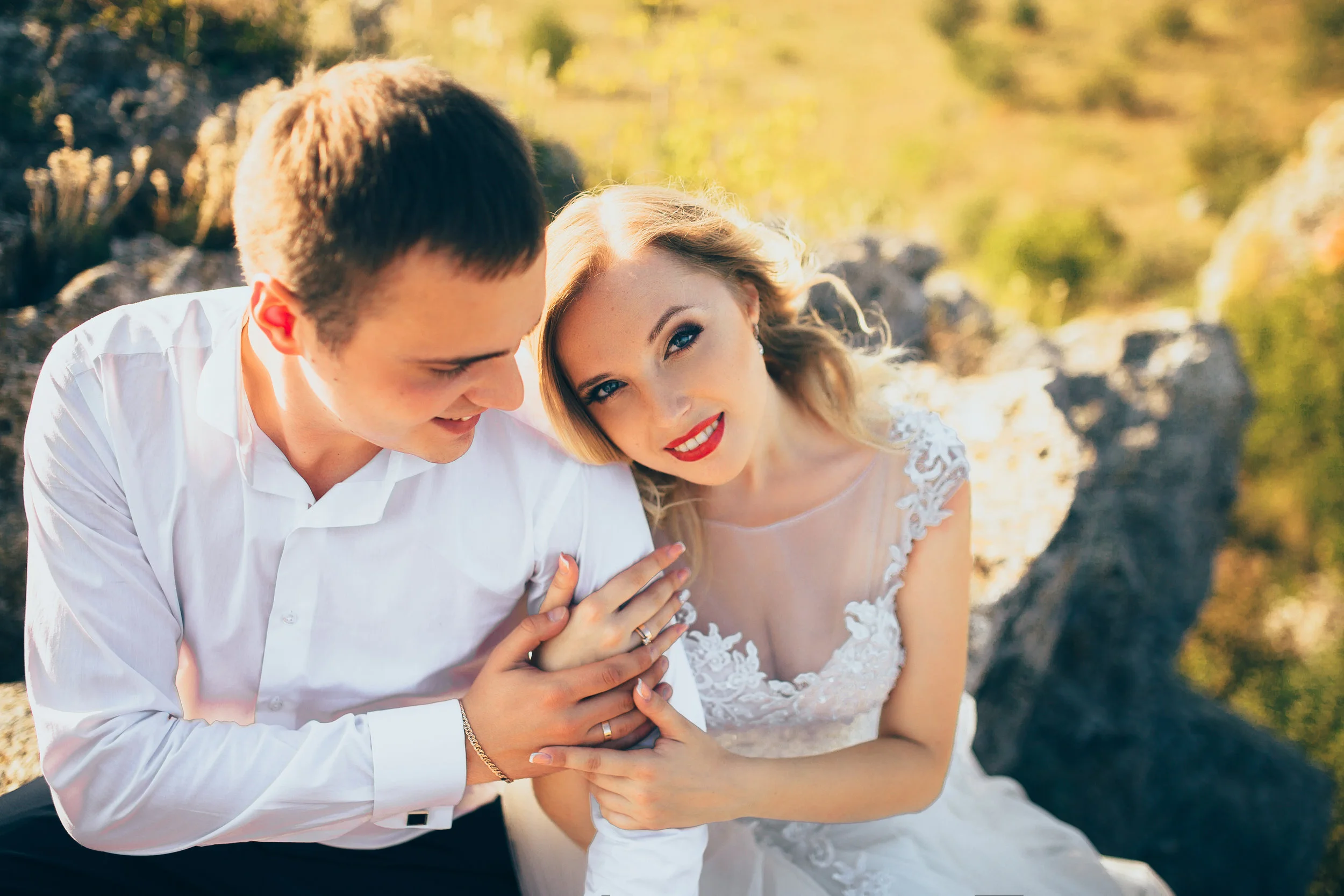 Gorgeous bride, groom kissing and hugging near the cliffs with stunning views