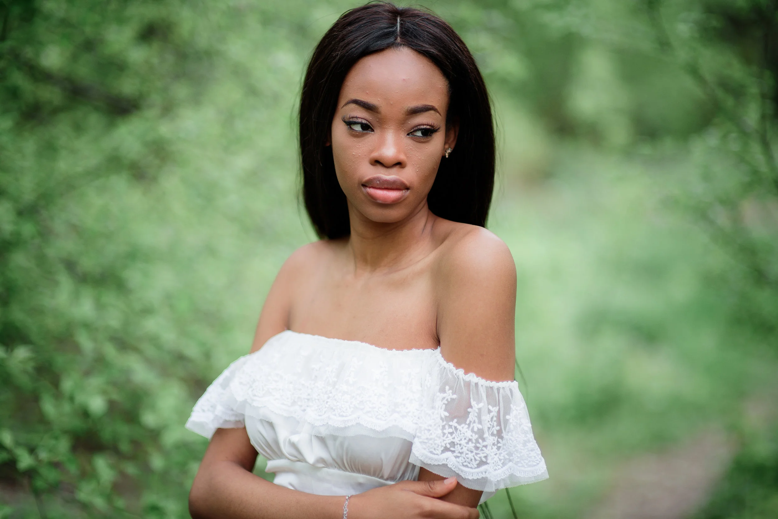 Beautiful Afro-American woman poses in white dress with open shoulders