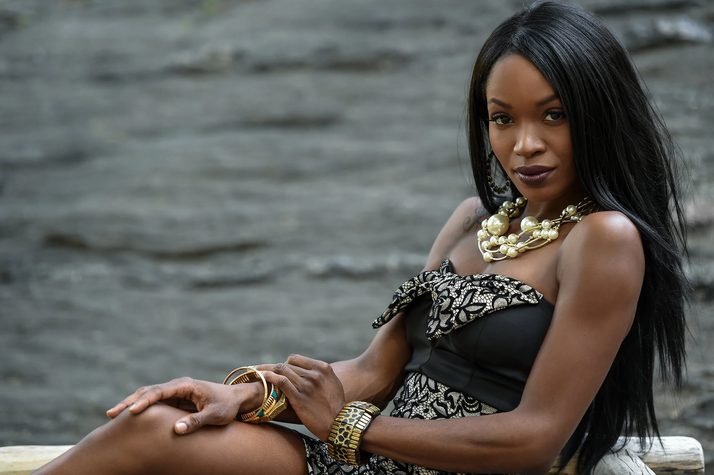Exotic looking African American woman posing in front of camera wearing black mini dress and jewellery with pearls.
