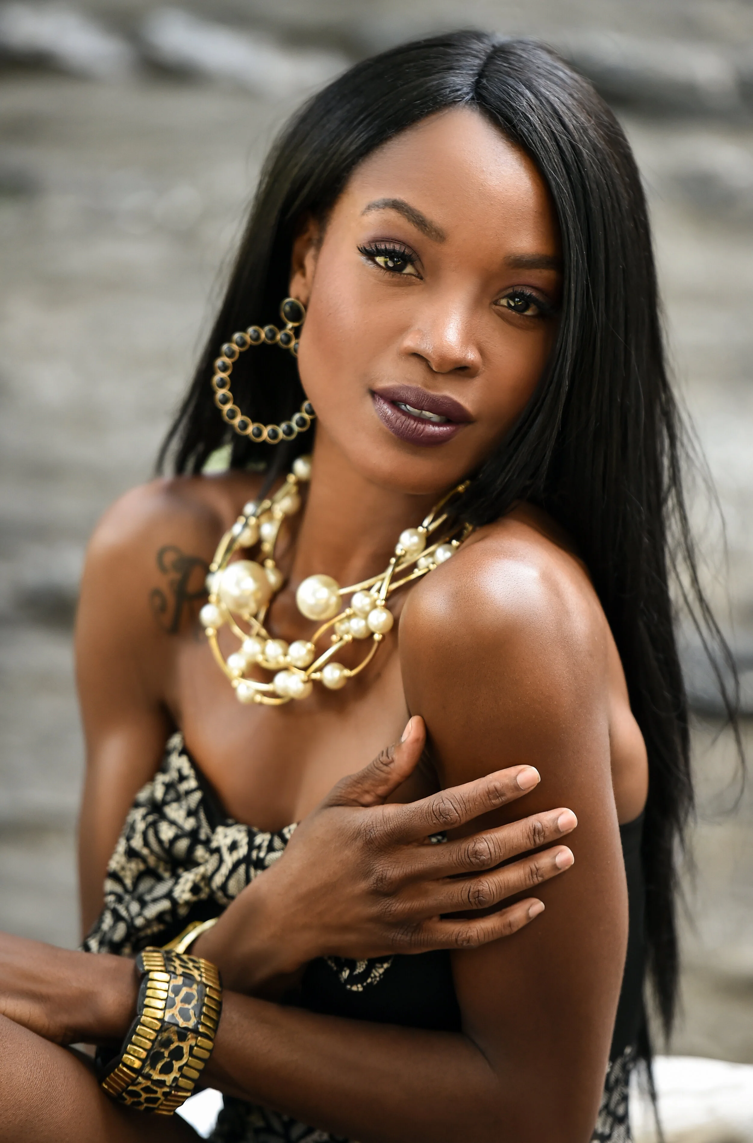Exotic looking African American woman wearing black mini dress and jewellery with pearls posing sexy at outside location.