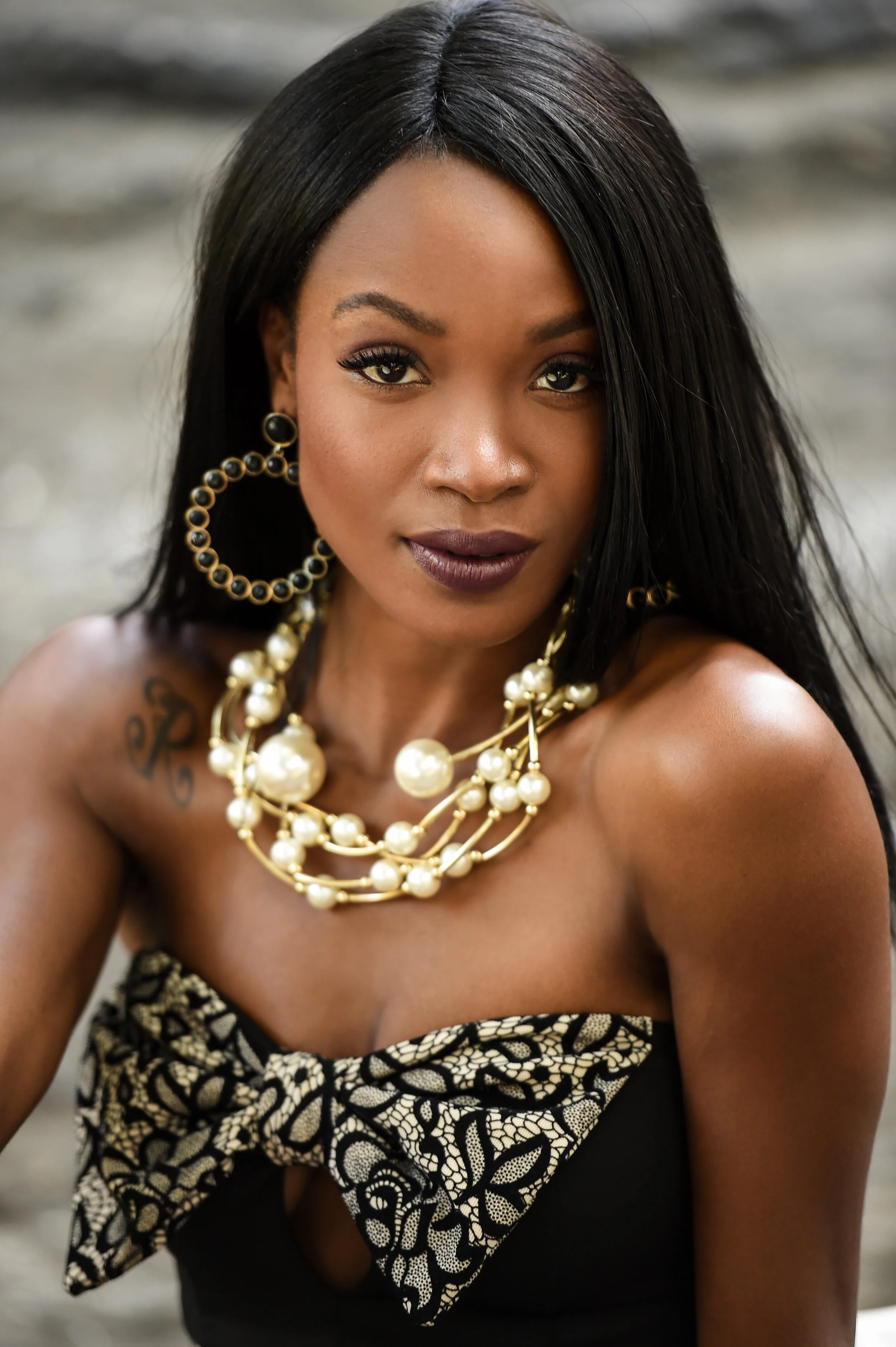Portrait of exotic looking African American woman in black mini dress wearing massive jewellery with pearls.