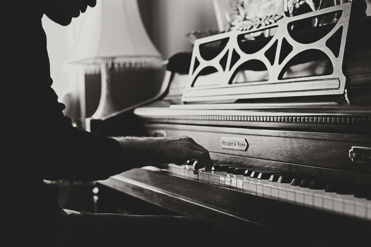 An adult musician playing an upright piano