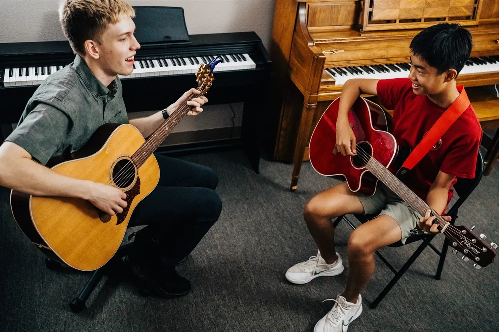 Guitar teacher and student making music together