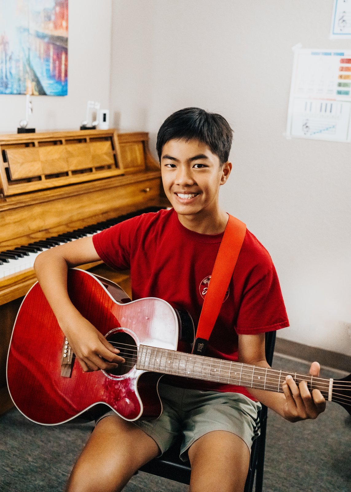 A Heart Beats acoustic guitar student smiling with his red guitar