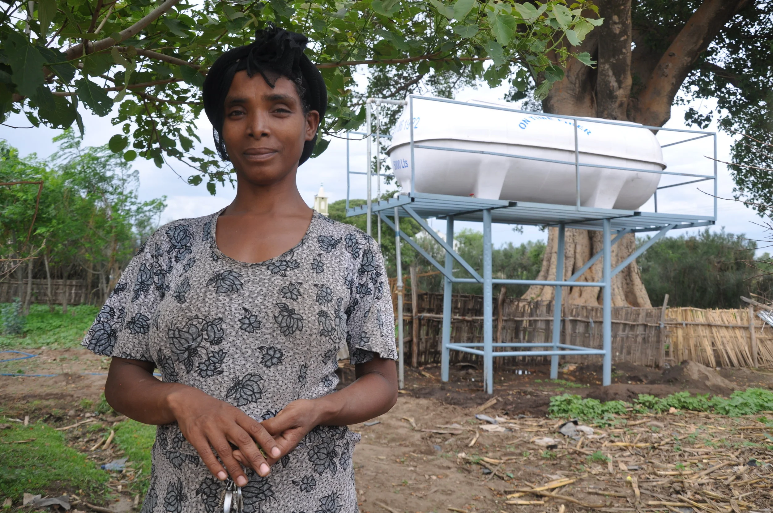(Fig. 1) Mammay next to the new water tank filled by a solar powered pump. 