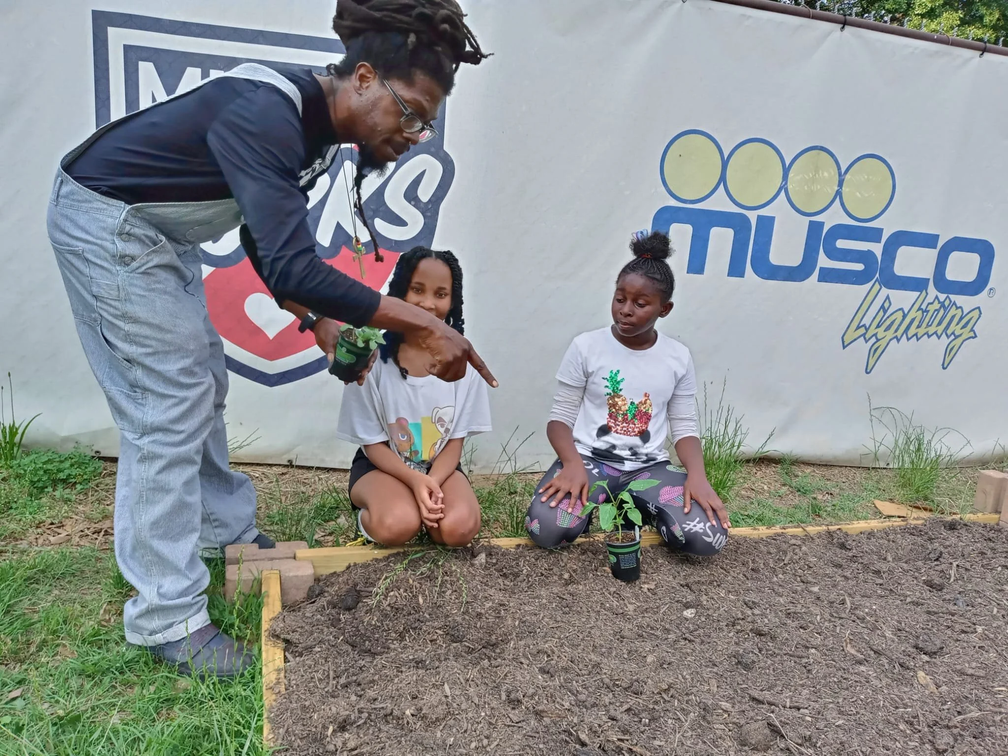 Coach Kwame helping kids plant the vegetables