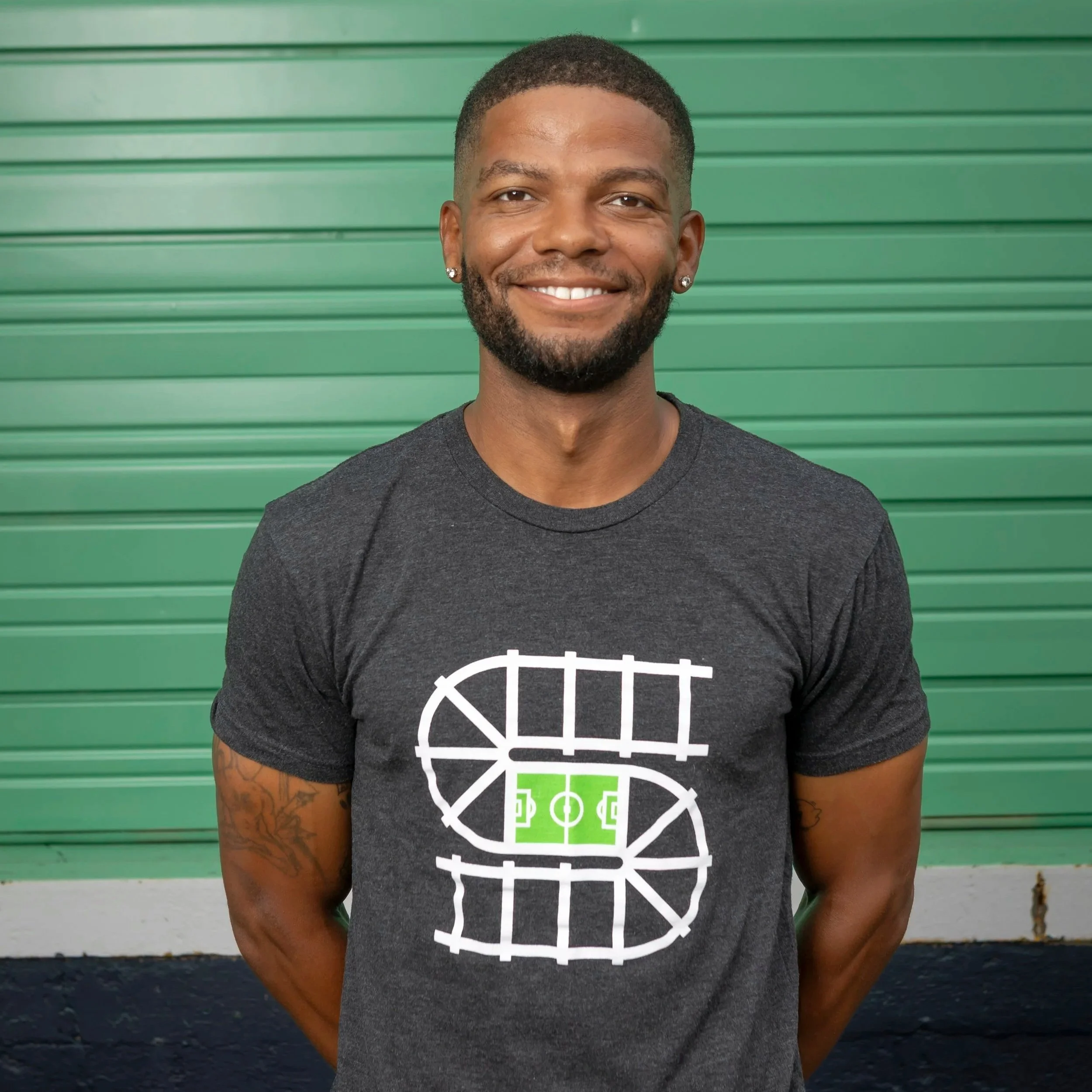 Smiling person wearing a black Adidas jacket with "Soccer in the Streets" logo and initials A.G.