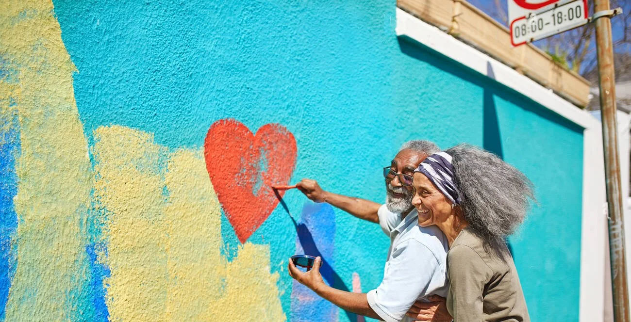 happy-senior-couple-painting-heart-shape-mural-on-sunny-wall-RRTN26.jpg