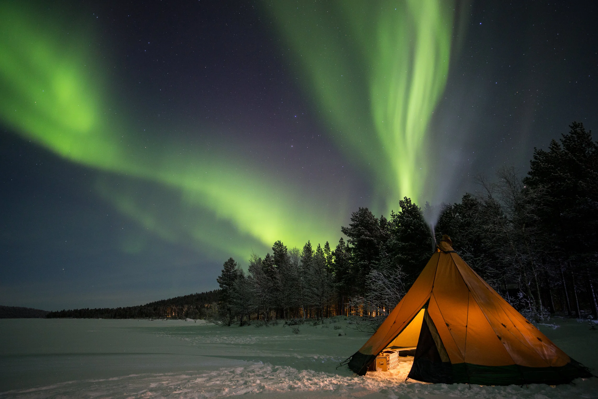 Aurora Borealis over a fire tipi on the shore of Ukonjarvi.