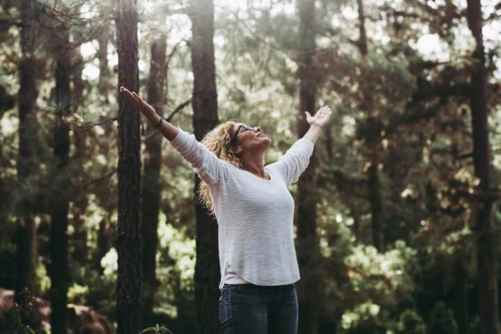 Woman standing in the forest with arms raised.jpg