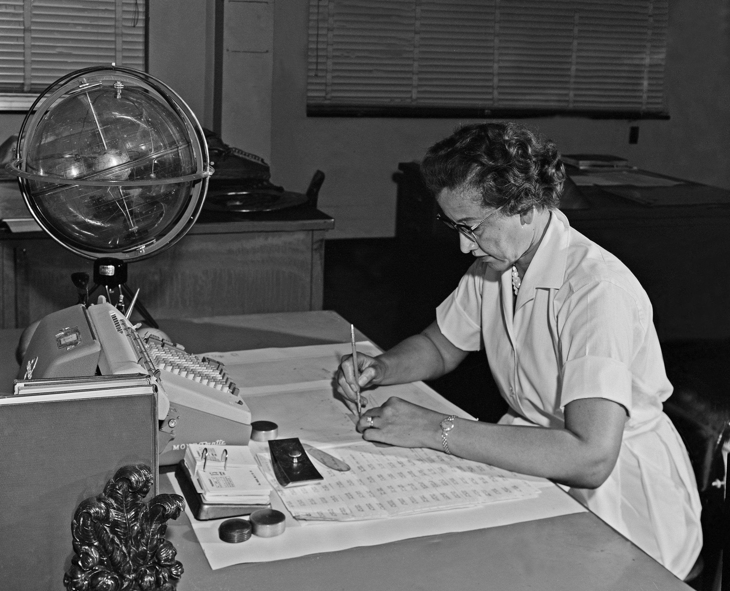 Katherine Johnson sits at her desk with a globe, or "Celestial Training Device." Credits: NASA.