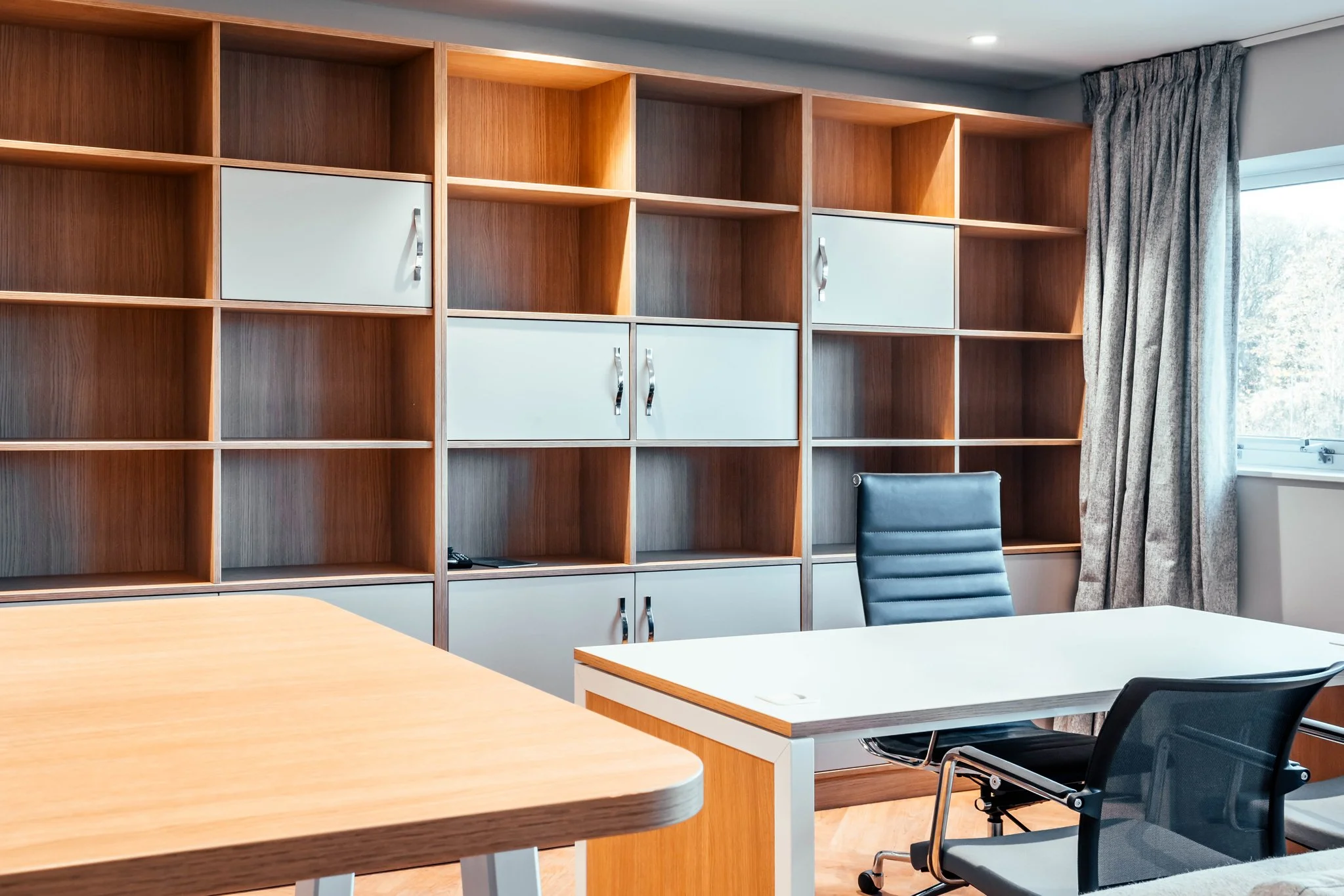Bielsa's office at Thorp Arch, with a full-height oak and grey shelving wall, a desk and a meeting table