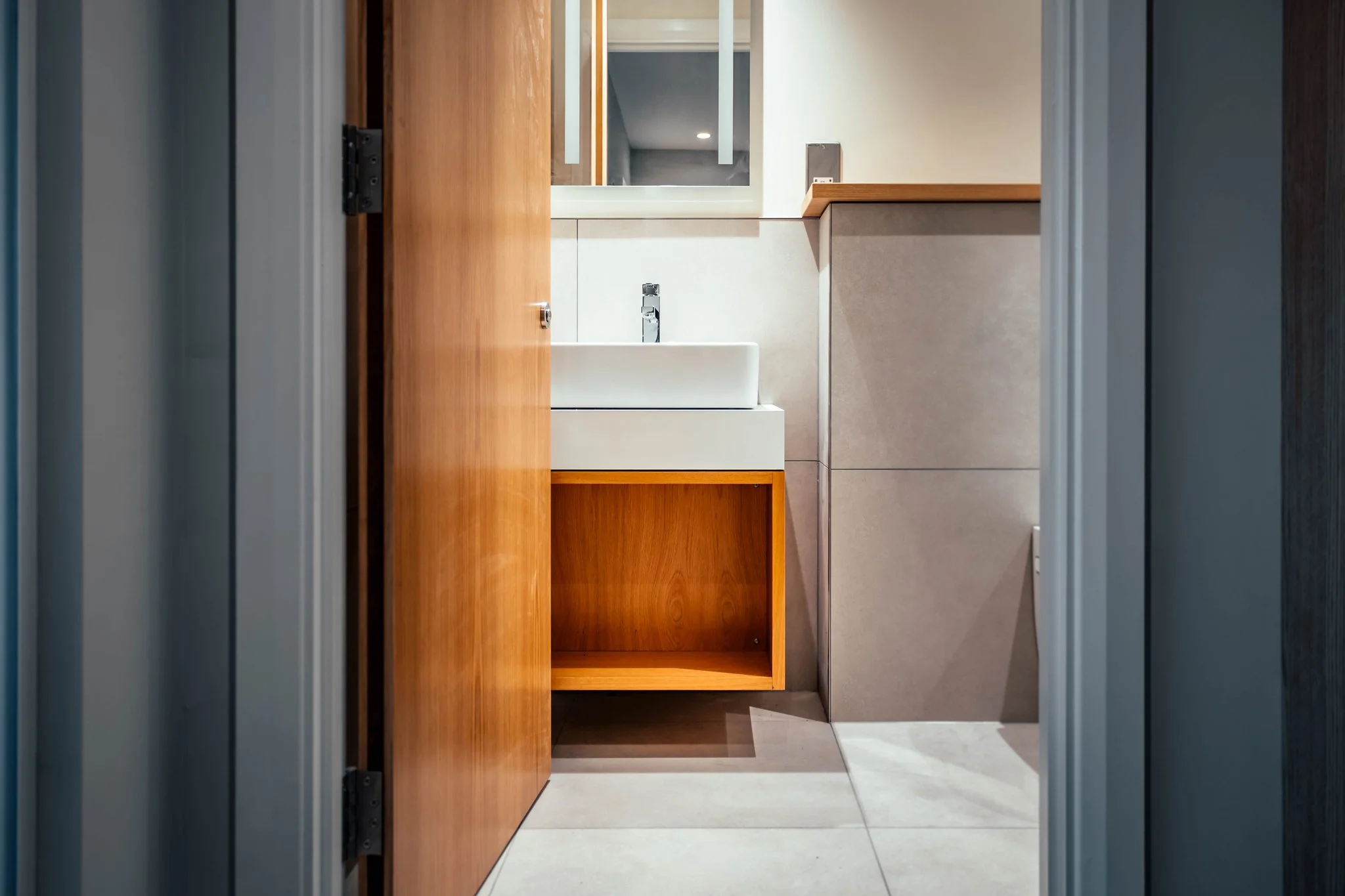 En-suite in Bielsa's office suite, with a floating oak vanity and an illuminated mirror