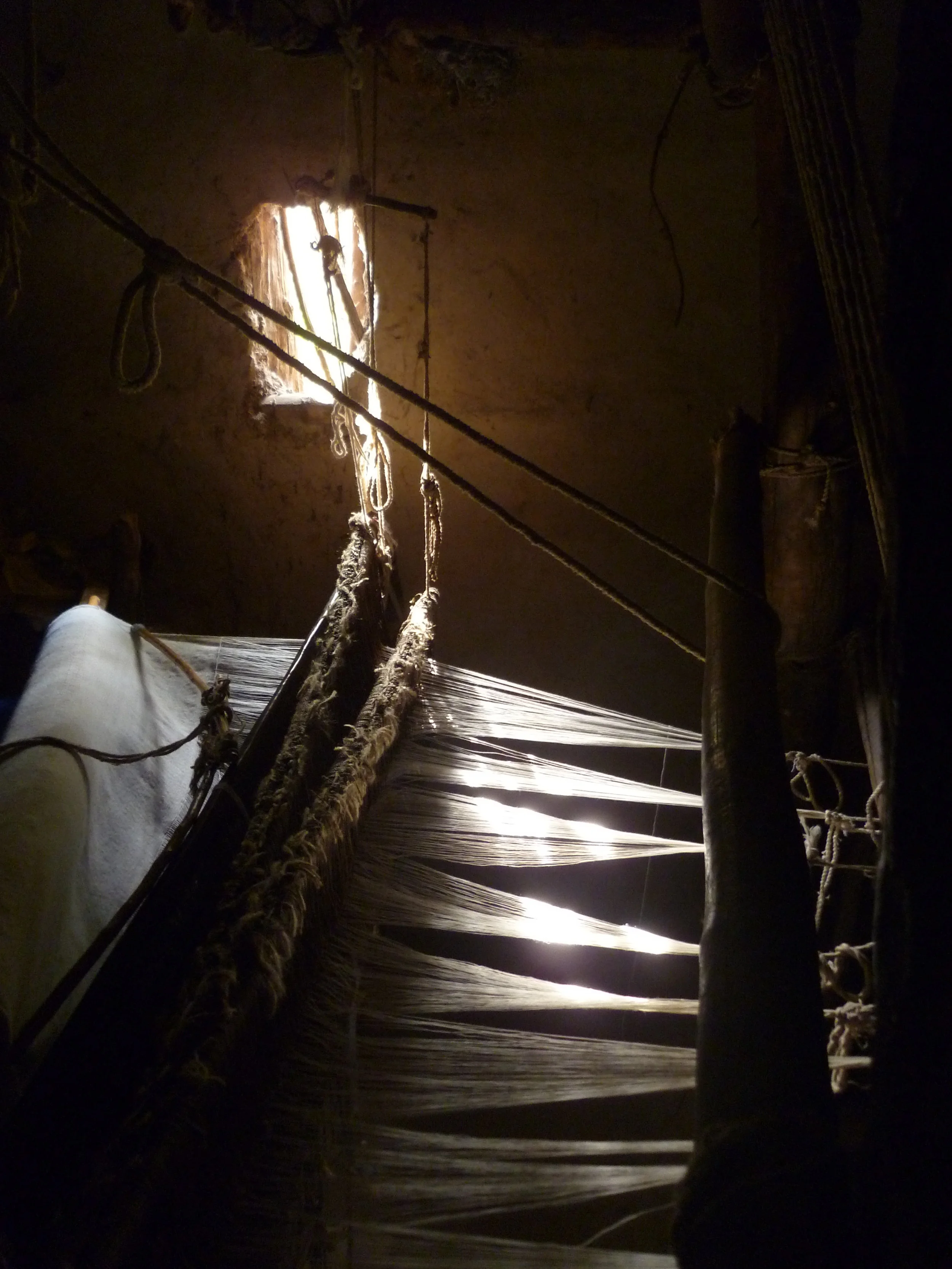 Sunlight pouring through the workshop windows illuminating the intricate Awra Amba weaving...