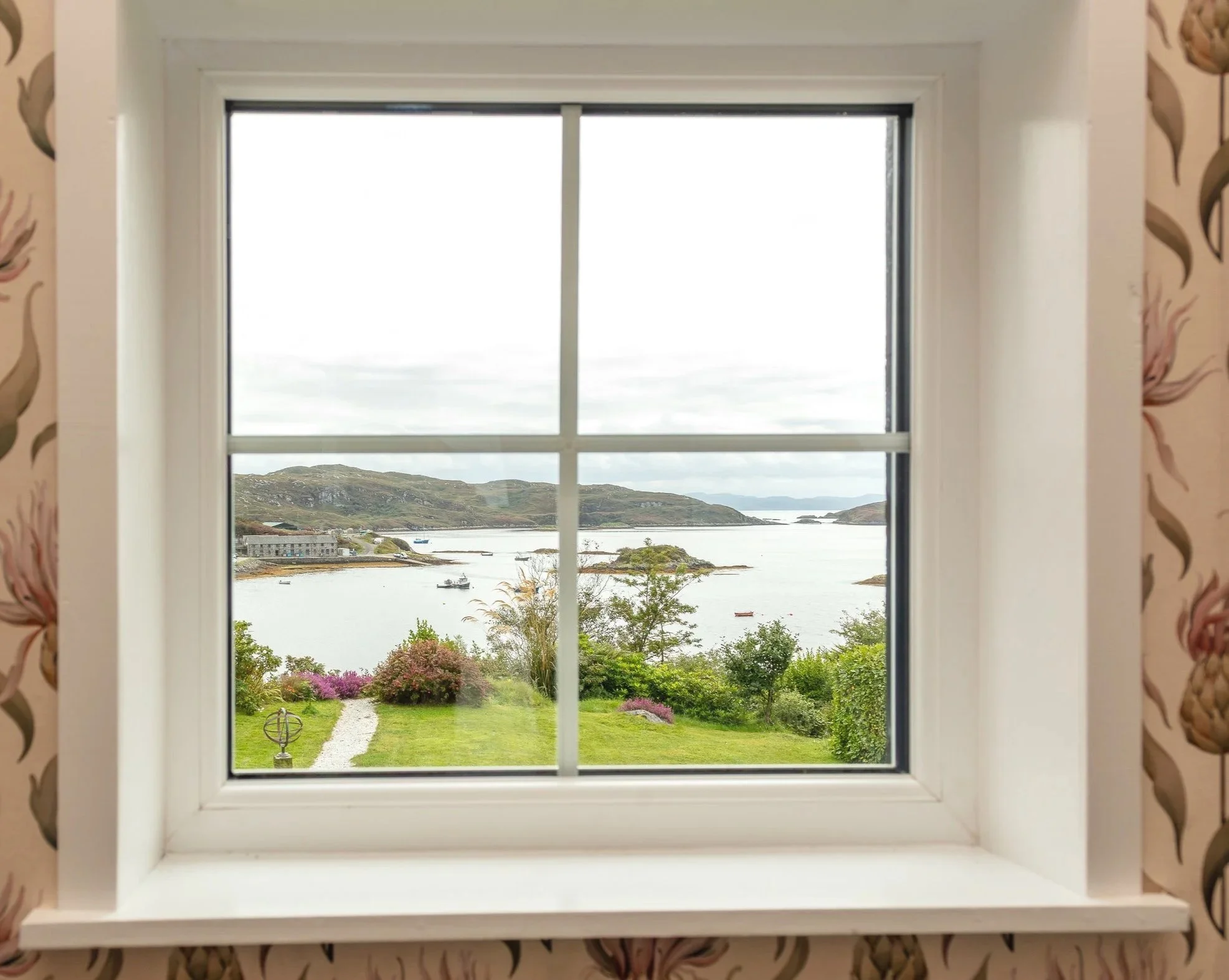 Window on landing looking out across to Badcall Bay,.  White window frame with thistle patterned wall paper