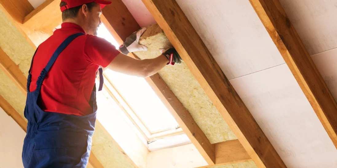 A professional insulation installer setting new insulation in between wooden supports in a residential property.