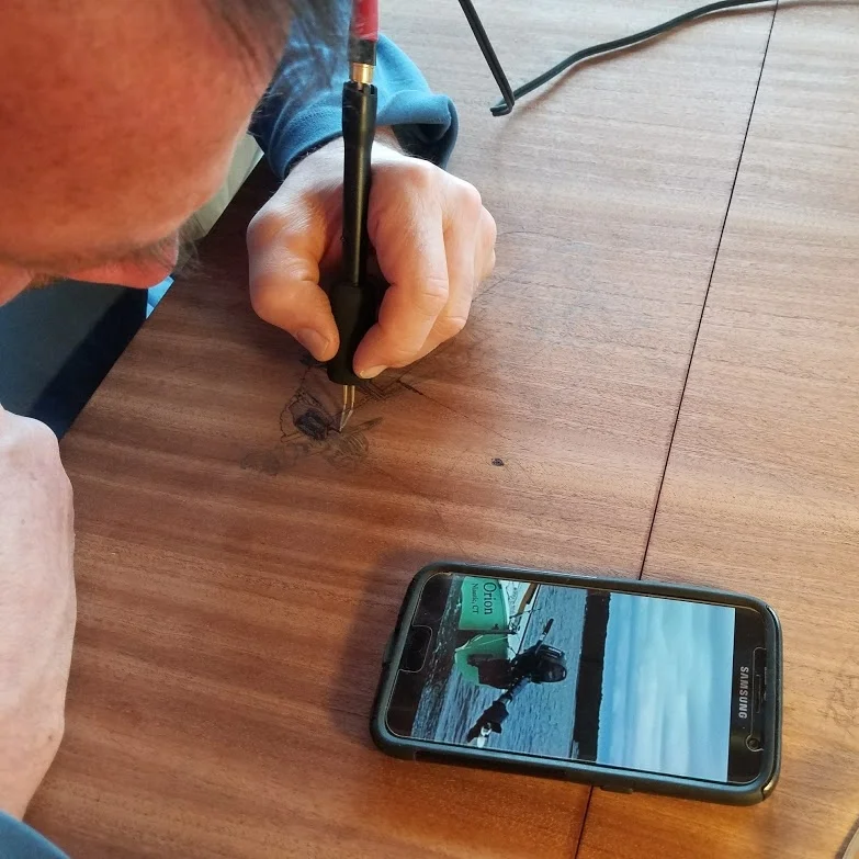 Getting the details of the outboard motor just right by looking at a photo of ORION on his phone.