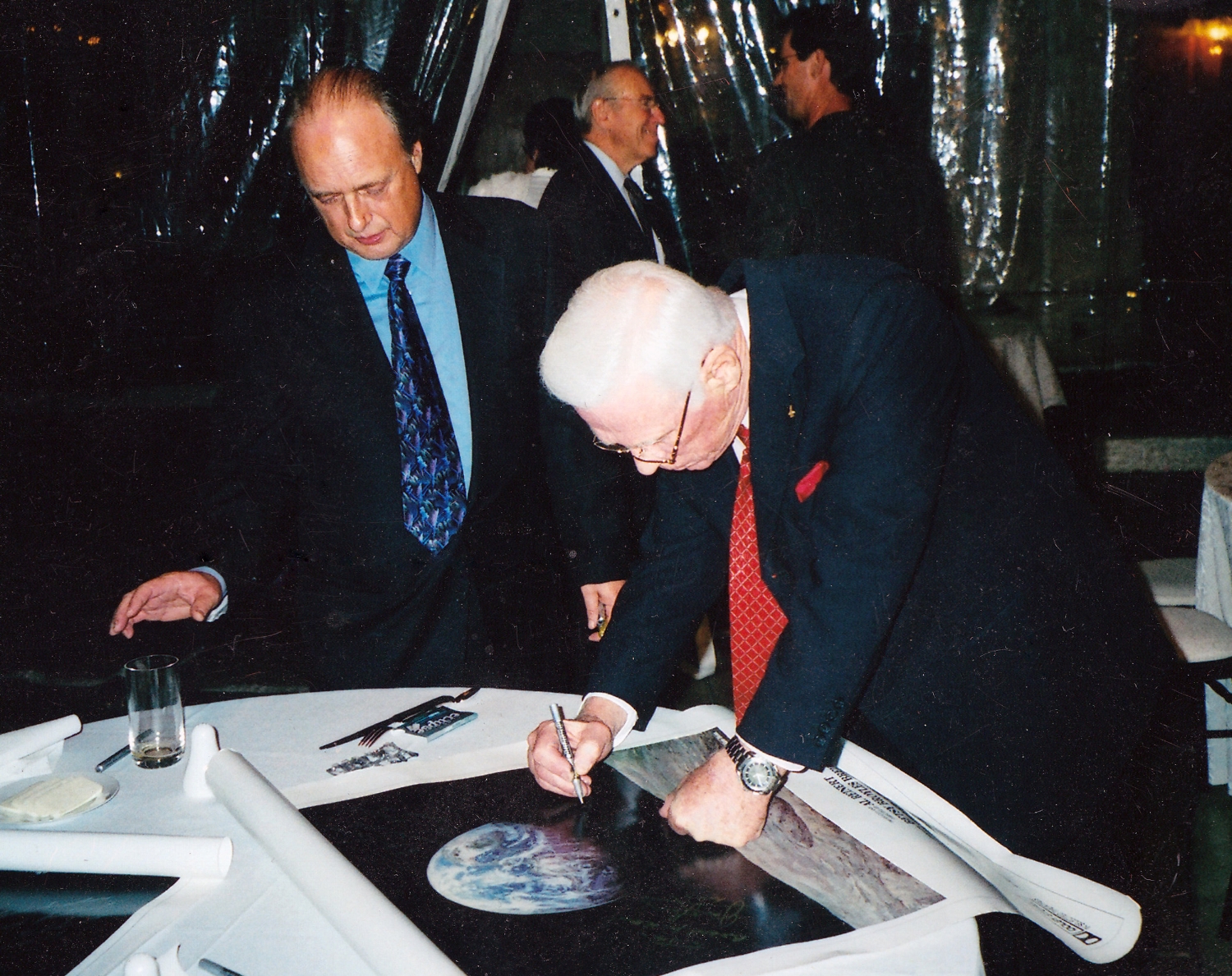 Astronaut Gene Cernan, the last man to walk on the moon, signs a For All Mankind poster with filmmaker Al Reinert. Photo Courtesy Al Reinert