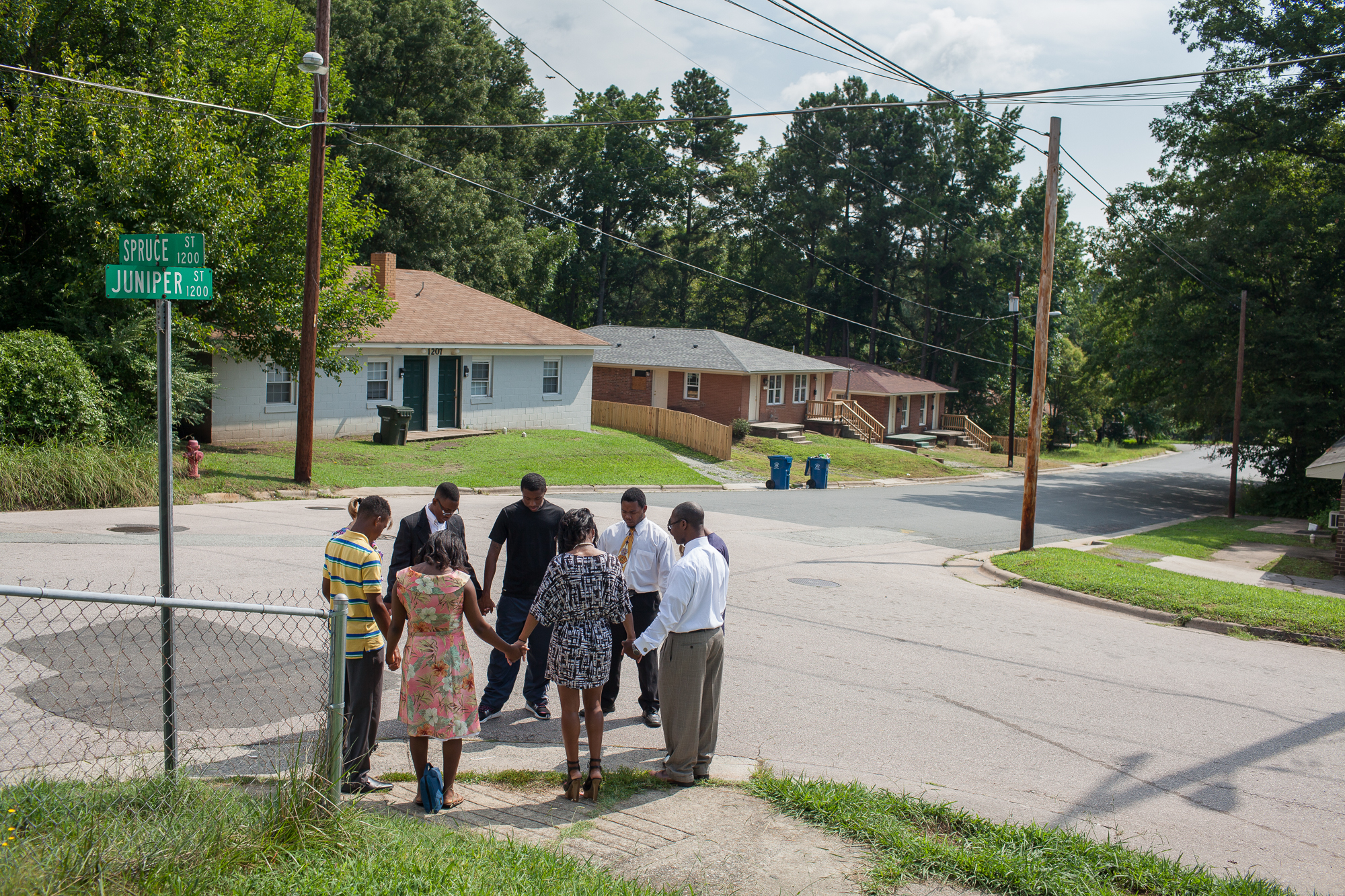  Congregants of Mount Gilead Baptist Church, led by Pastor Sanders Tate (far right), pray for peace at an East Durham intersection at the beginning of the 2013 school year. 