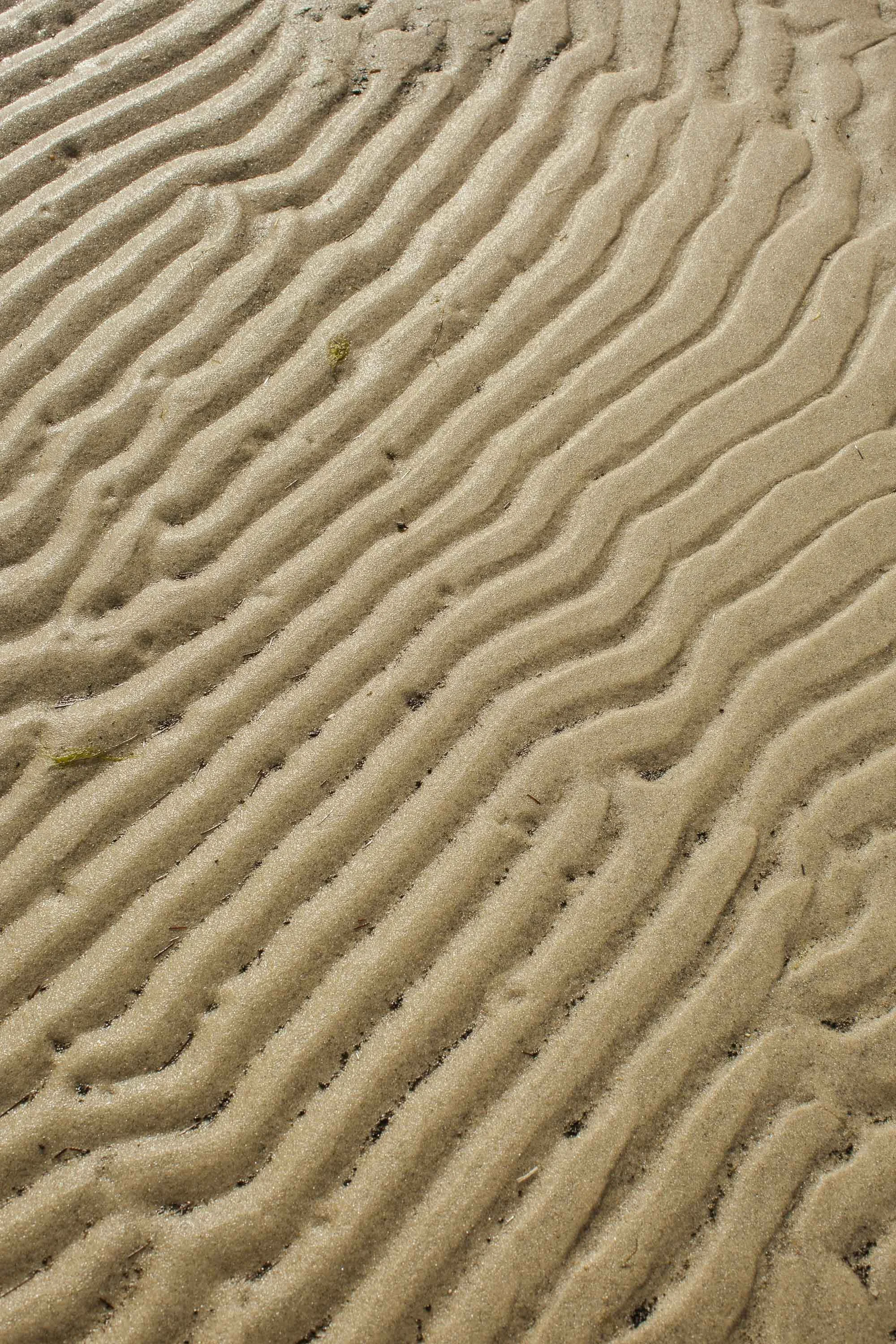 Ripples in the sand left by wave action are visible at low tide.