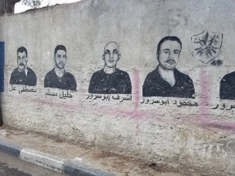 The faces of Palestinian men painted on the walls of the camp. These paintings are in memory of men who have been sentenced to life in Israeli prisons. (Photo by Charlie Finn)