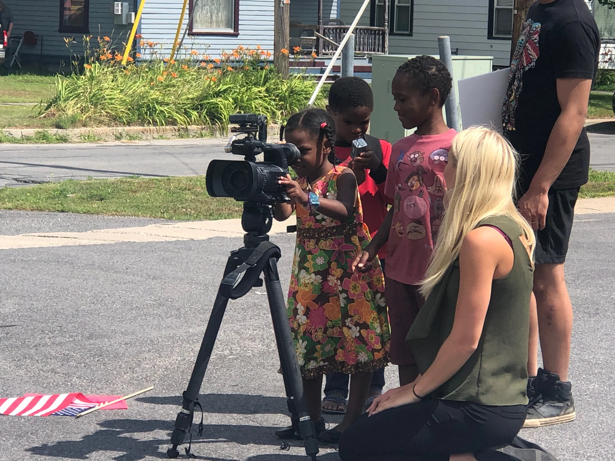 Sarah Evans, Noah Evans (center), and Tre-saiah Evans, march organizer Jennifer Baxtron's grandchildren, take a look through a news camera with WWNY's Emily Griffin, who was reporting on the march in Potsdam.