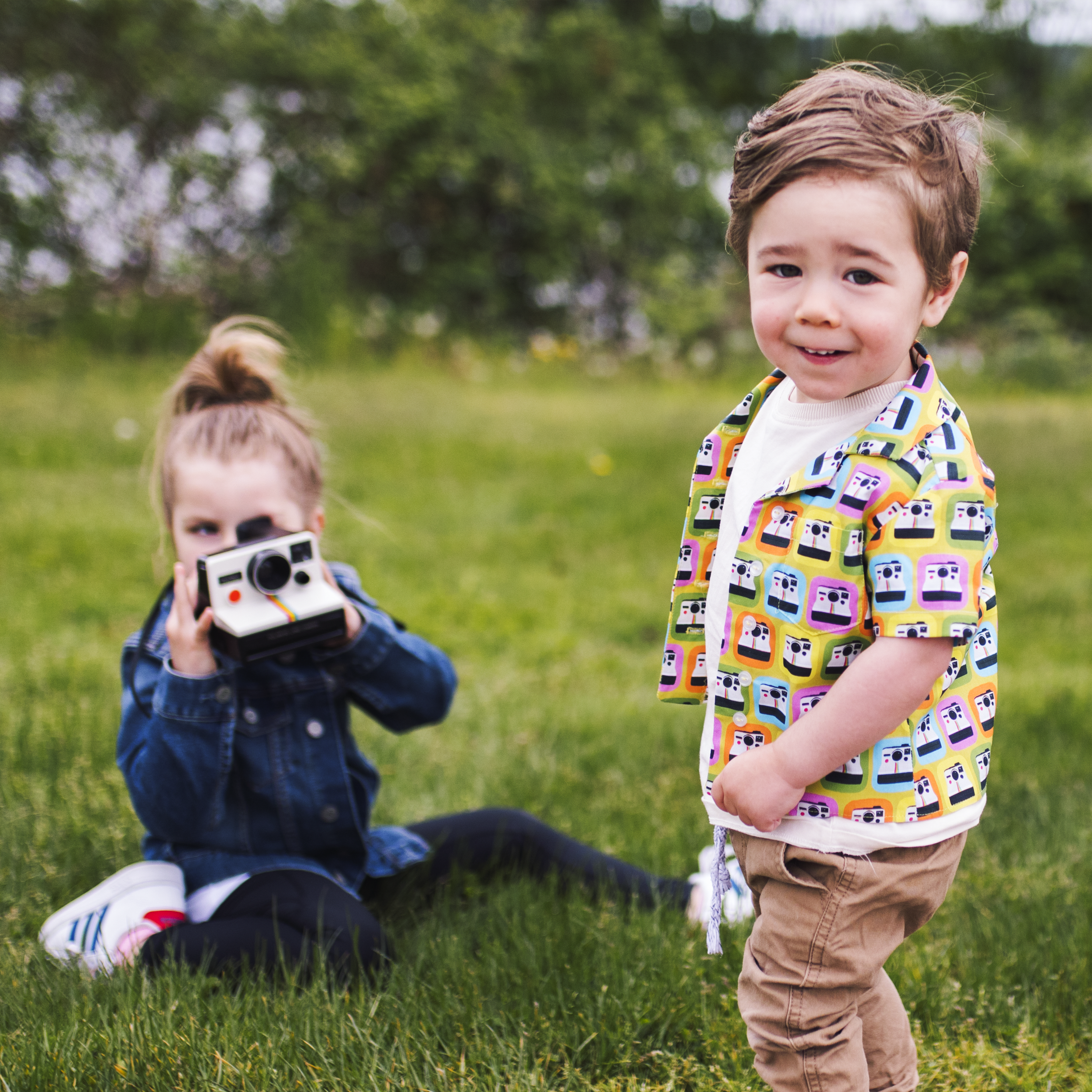 little boy in park with girl taking his picture.png
