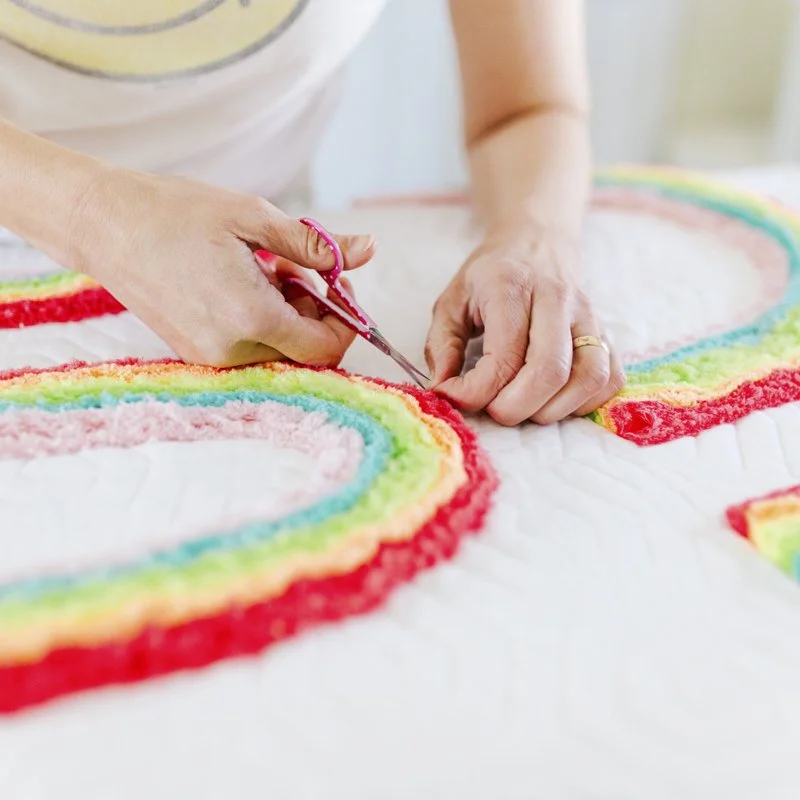 lysa flower with a small pair of scissors trimming a chenille quilt she designed and made.jpg