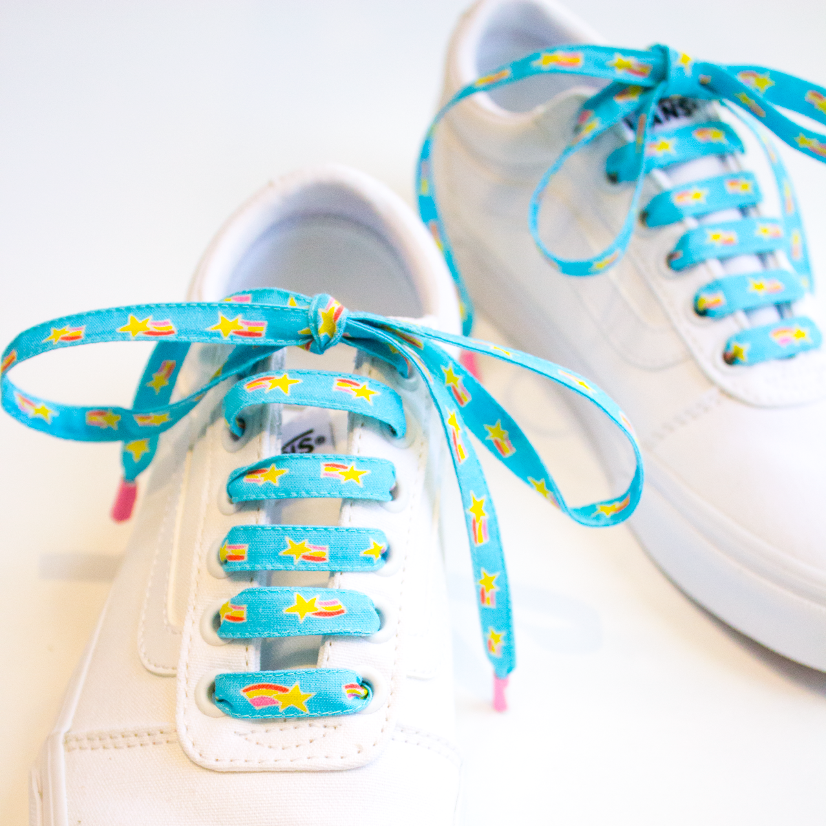 white van shoes with blue lysa flower star and rainbows printed on them.png