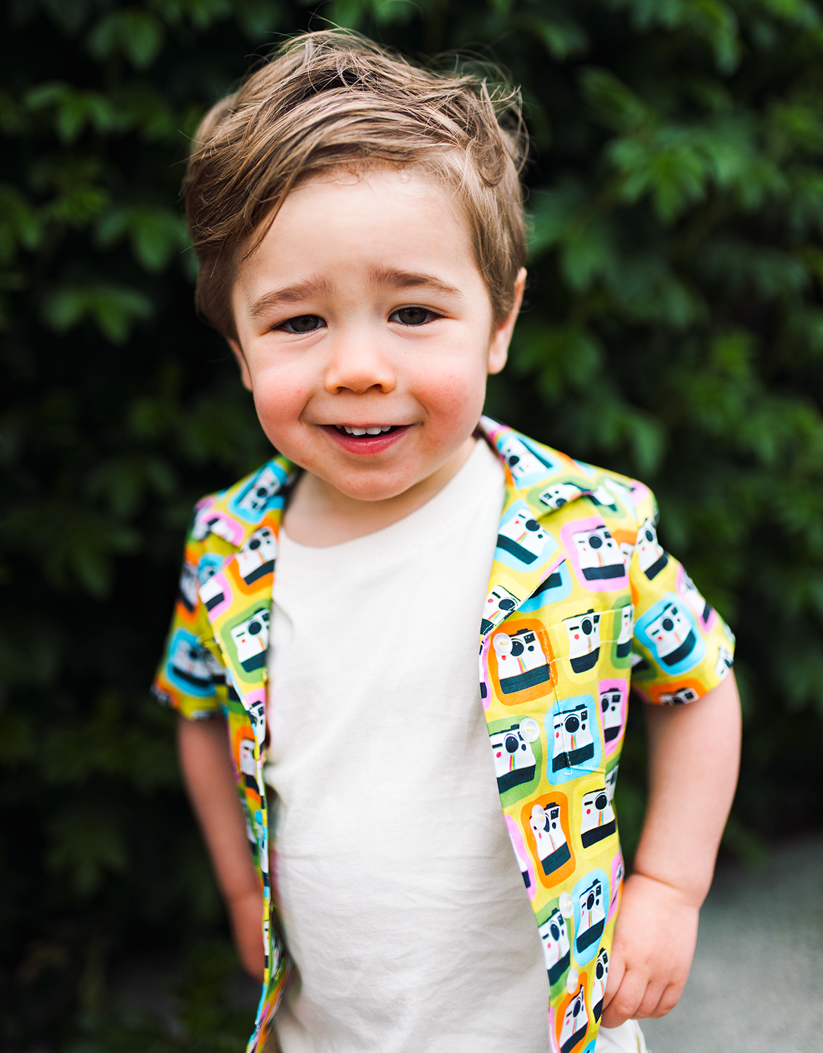 cute little boy with shirt of lysa flower design of polarid cameras on a backgroudn of mustard yellow.png